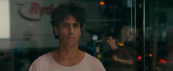 Movie still from “The Dictator” (2012), directed by Larry Charles – A person wearing a pink t - shirt; Close Up shot, Over the shoulder angle