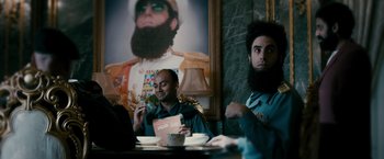 Movie still from “The Dictator” (2012), directed by Larry Charles – Two men sitting at a table eating food; Medium shot, Over the shoulder angle
