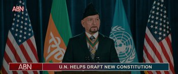 Movie still from “The Dictator” (2012), directed by Larry Charles – A man in a suit and a hat is speaking; Medium shot, High angle