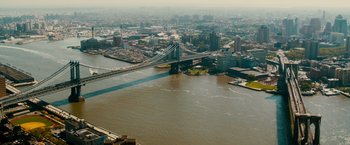 Movie still from “The Dictator” (2012), directed by Larry Charles – An aerial view of a city with a bridge in the middle of it; Extreme Wide shot, High angle