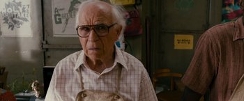 Movie still from “The Dictator” (2012), directed by Larry Charles – An old man wearing glasses and an apron; Close Up shot, High angle