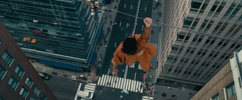Movie still from “The Dictator” (2012), directed by Larry Charles – A man hanging from a wire above a city street; Extreme Wide shot, Overhead angle