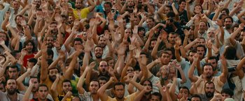 Movie still from “The Dictator” (2012), directed by Larry Charles – A large group of people with their hands up; Extreme Wide shot, High angle