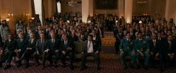 Movie still from “The Dictator” (2012), directed by Larry Charles – A group of people in suits sitting in front of a crowd; Wide shot, High angle