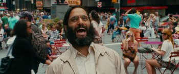 Movie still from “The Dictator” (2012), directed by Larry Charles – A man with a beard and glasses is smiling; Close Up shot, Over the shoulder angle