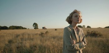 Movie still from “The Dig” (2021), directed by Simon Stone – A woman standing in the middle of an open field; Medium shot, Low angle