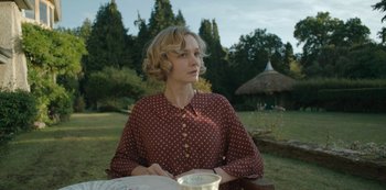 Movie still from “The Dig” (2021), directed by Simon Stone – A woman sitting at a table in a field; Medium shot, Over the shoulder angle