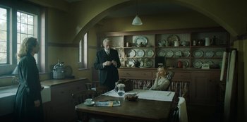 Movie still from “The Dig” (2021), directed by Simon Stone – An older man and a woman in a dining room; Wide shot, Low angle