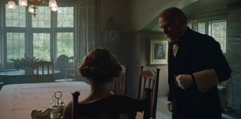Movie still from “The Dig” (2021), directed by Simon Stone – An older man and a young woman sitting at a dining room table; Medium shot, Over the shoulder angle