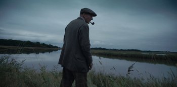 Movie still from “The Dig” (2021), directed by Simon Stone – An older man standing in front of a body of water; Medium shot, Low angle