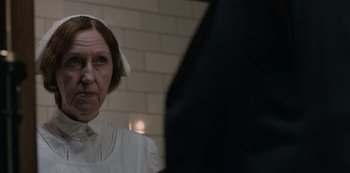 Movie still from “The Dig” (2021), directed by Simon Stone – An older woman wearing a nurse's uniform; Close Up shot, Over the shoulder angle