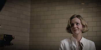 Movie still from “The Dig” (2021), directed by Simon Stone – A woman in a white shirt is sitting in front of a brick wall; Close Up shot, Low angle