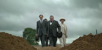 Movie still from “The Dig” (2021), directed by Simon Stone – A group of men walking across a dirt field; Wide shot, Low angle