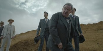 Movie still from “The Dig” (2021), directed by Simon Stone – A group of men standing on top of a dirt hill; Medium shot, Low angle