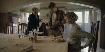 Movie still from “The Dig” (2021), directed by Simon Stone – A man and a woman standing at a dinner table; Medium shot, Over the shoulder angle