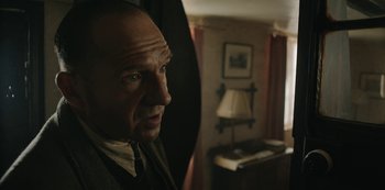 Movie still from “The Dig” (2021), directed by Simon Stone – A man in a suit and tie looking at the camera; Close Up shot, Over the shoulder angle
