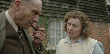 Movie still from “The Dig” (2021), directed by Simon Stone – An older man smoking a pipe next to an older woman; Close Up shot, Over the shoulder angle