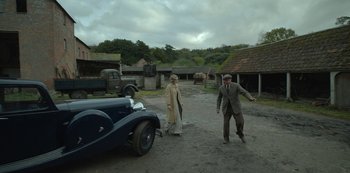 Movie still from “The Dig” (2021), directed by Simon Stone – A man and a woman walking in front of an antique car; Wide shot, High angle