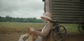 Movie still from “The Dig” (2021), directed by Simon Stone – A woman sitting in a chair holding a purse; Medium shot, Low angle