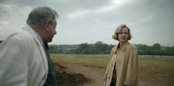 Movie still from “The Dig” (2021), directed by Simon Stone – A woman in a trench coat standing next to an older man; Medium shot, Over the shoulder angle