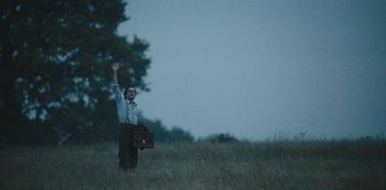 Movie still from “The Dig” (2021), directed by Simon Stone – A man standing in a field holding a briefcase; Wide shot, Low angle