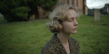 Movie still from “The Dig” (2021), directed by Simon Stone – A woman with her eyes closed in a field; Close Up shot, Over the shoulder angle