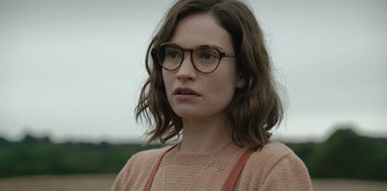 Movie still from “The Dig” (2021), directed by Simon Stone – A person wearing glasses and a sweater; Close Up shot, Over the shoulder angle