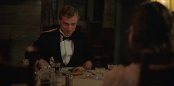 Movie still from “The Dig” (2021), directed by Simon Stone – A man sitting at a table with a plate of food; Medium shot, Over the shoulder angle