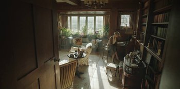 Movie still from “The Dig” (2021), directed by Simon Stone – A woman sitting at a table in a living room; Wide shot, High angle
