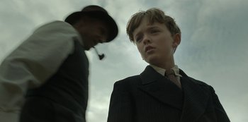 Movie still from “The Dig” (2021), directed by Simon Stone – A young man in a suit and tie standing next to another young man in a suit and tie; Close Up shot, Low angle
