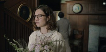 Movie still from “The Dig” (2021), directed by Simon Stone – A woman with glasses holding a bouquet of flowers; Close Up shot, Over the shoulder angle