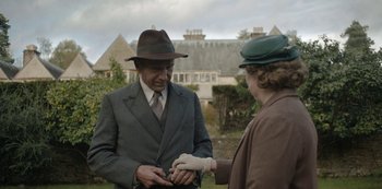 Movie still from “The Dig” (2021), directed by Simon Stone – An older man in a suit and a woman in a hat; Medium shot, Over the shoulder angle