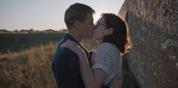 Movie still from “The Dig” (2021), directed by Simon Stone – A man and a woman kissing in front of a stone wall; Close Up shot, Low angle