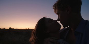 Movie still from “The Dig” (2021), directed by Simon Stone – A man and a woman kissing in a field at sunset; Close Up shot, Low angle