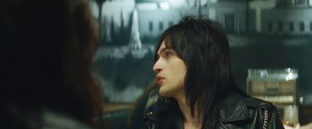 Movie still from “The Dirt” (2019), directed by Jeff Tremaine – A man with long black hair looking to his left; Close Up shot, Over the shoulder angle