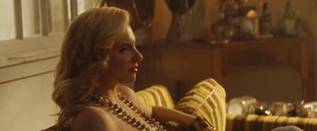Movie still from “The Dirt” (2019), directed by Jeff Tremaine – A woman sitting on a couch wearing a necklace; Close Up shot, Over the shoulder angle