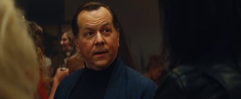 Movie still from “The Dirt” (2019), directed by Jeff Tremaine – An older man in a blue jacket looks at the camera; Close Up shot, Over the shoulder angle