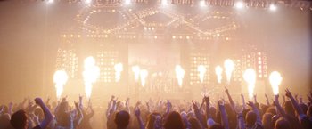 Movie still from “The Dirt” (2019), directed by Jeff Tremaine – A crowd of people in front of a stage with lights; Extreme Wide shot, High angle