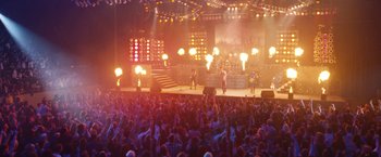 Movie still from “The Dirt” (2019), directed by Jeff Tremaine – A crowd of people watching a band perform on a stage; Extreme Wide shot, High angle