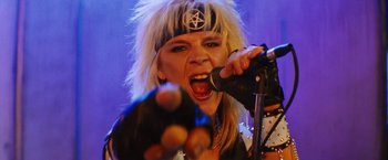 Movie still from “The Dirt” (2019), directed by Jeff Tremaine – A person with a microphone in a room; Close Up shot, Overhead angle