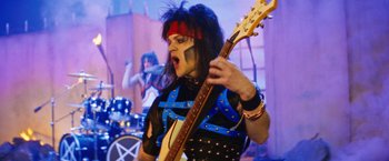 Movie still from “The Dirt” (2019), directed by Jeff Tremaine – A person with a black and blue outfit on holding a guitar; Medium shot, Low angle