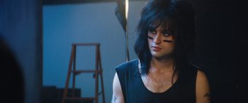 Movie still from “The Dirt” (2019), directed by Jeff Tremaine – A person with long black hair and a black shirt; Medium shot, Low angle