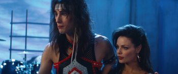 Movie still from “The Dirt” (2019), directed by Jeff Tremaine – A man and a woman standing next to each other; Medium shot, Over the shoulder angle