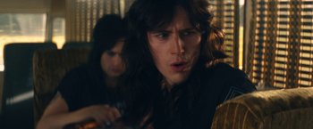 Movie still from “The Dirt” (2019), directed by Jeff Tremaine – A man with long brown hair is looking at the camera; Close Up shot, Over the shoulder angle