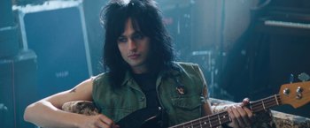 Movie still from “The Dirt” (2019), directed by Jeff Tremaine – A man with long black hair playing an electric guitar; Close Up shot, Low angle