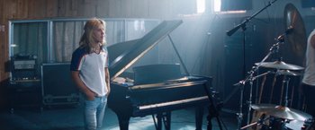 Movie still from “The Dirt” (2019), directed by Jeff Tremaine – A woman standing in front of a black piano; Medium shot, Low angle