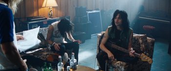 Movie still from “The Dirt” (2019), directed by Jeff Tremaine – A couple of people that are sitting on some chairs; Medium shot, Low angle