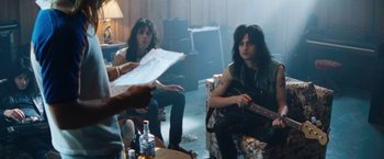 Movie still from “The Dirt” (2019), directed by Jeff Tremaine – A couple of people that are sitting in a room; Medium shot, Over the shoulder angle