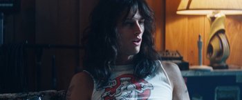 Movie still from “The Dirt” (2019), directed by Jeff Tremaine – A person with long black hair wearing a white shirt; Close Up shot, Low angle