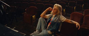 Movie still from “The Dirt” (2019), directed by Jeff Tremaine – A person sitting in a chair in a theater; Medium shot, High angle